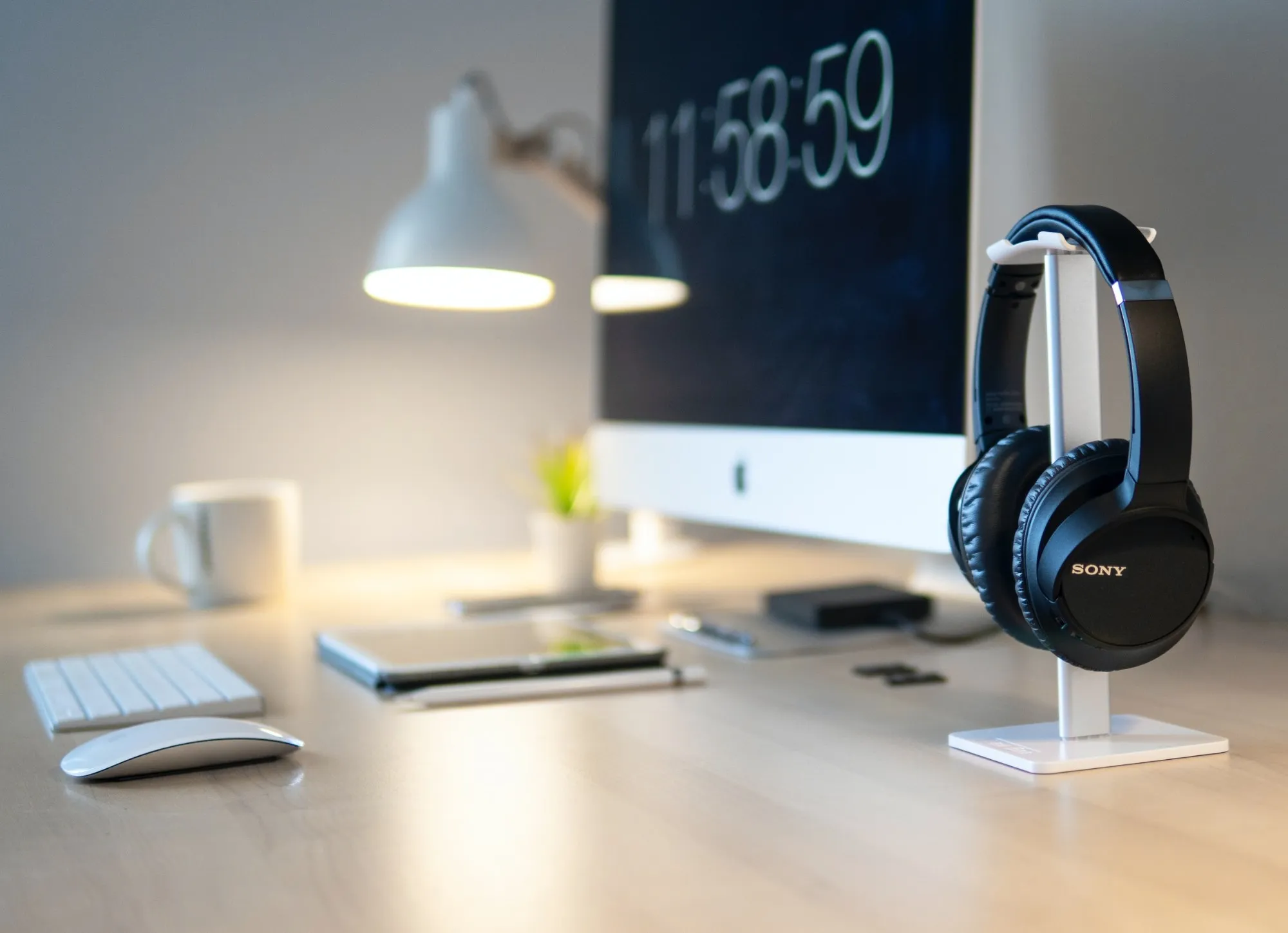 Aufgeräumter Arbeitsplatz mit Monitor, Lampe und Kopfhörern
